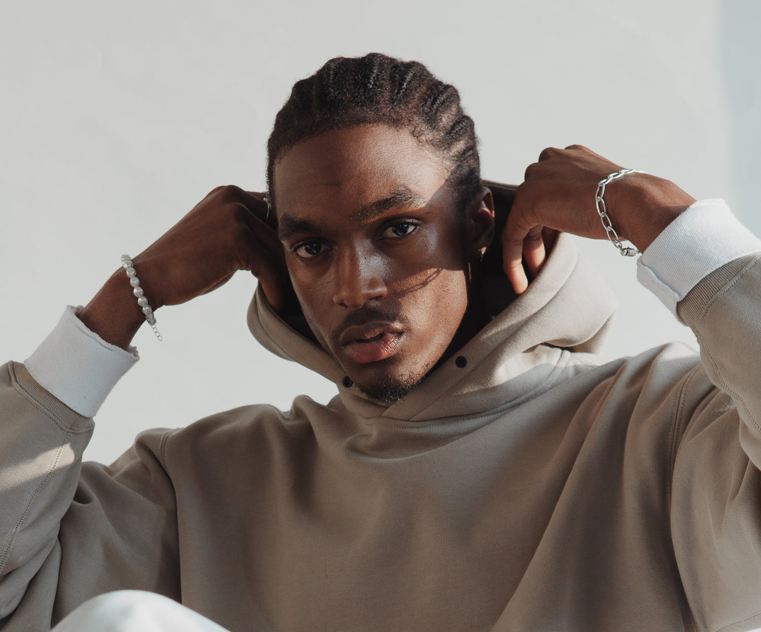 A young african-american man looking at the camera, wearing a grey jumper.